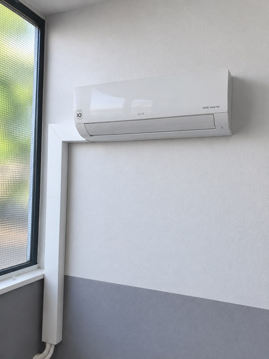 LG DUAL Inverter Innengerät der Klimaanlage an der Wand eines Pausenraumes neben dem Fenster